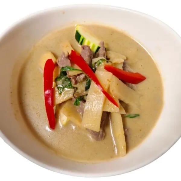 Royal Thai Orchid's green curry with beef, bamboo shoots, zucchini, and red peppers in a white bowl.