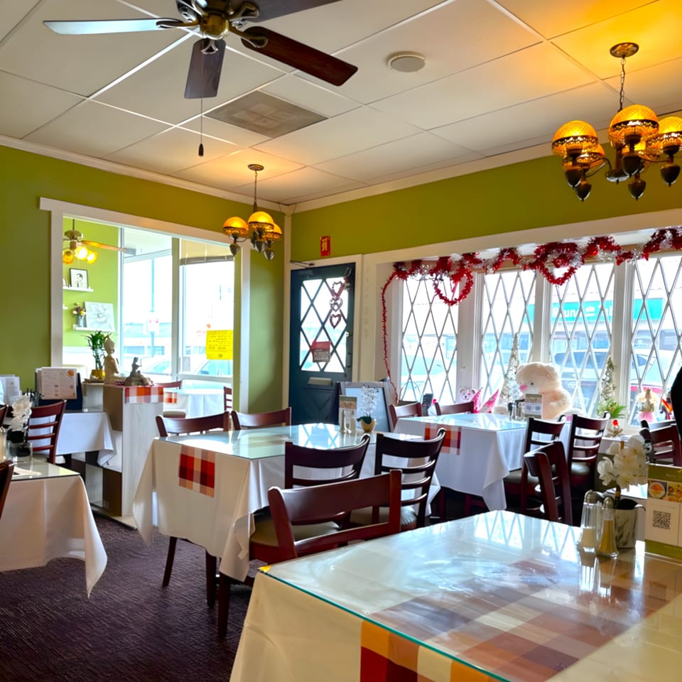 Interior of Royal Thai Orchid Restaurant with green walls, white tablecloths, and festive red and white decorations.