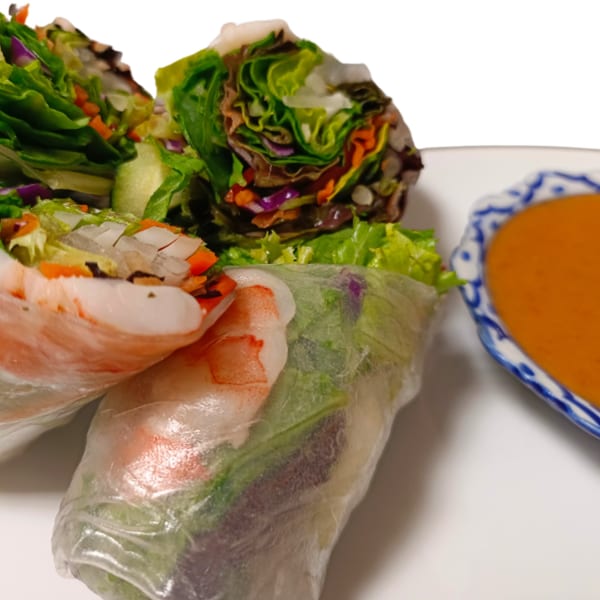 Fresh Thai spring rolls with shrimp and vegetables, served with a side of orange dipping sauce.