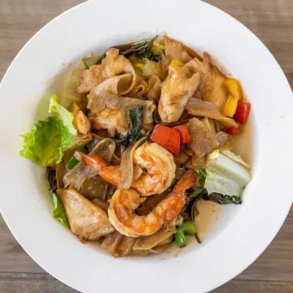 Royal Thai Orchid's Pad See Ew with shrimp, wide noodles, and colorful vegetables in a white bowl.