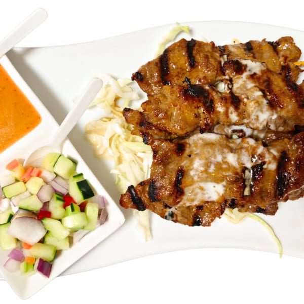 Grilled Thai chicken satay skewers with peanut sauce and cucumber salad on a white plate.